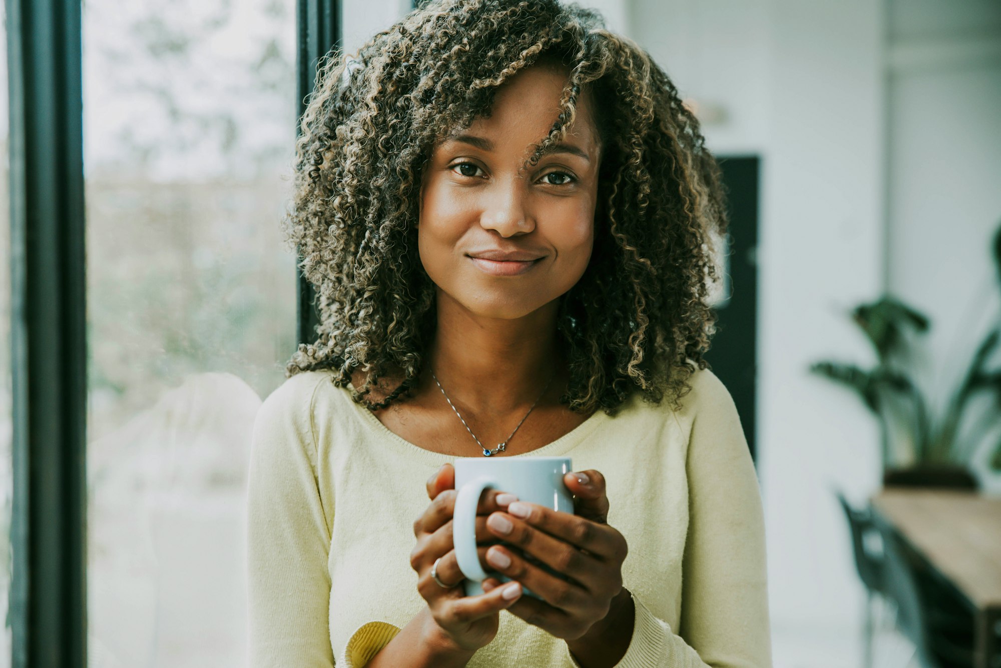 Portrait of young black woman holding cup of tea looking at camera